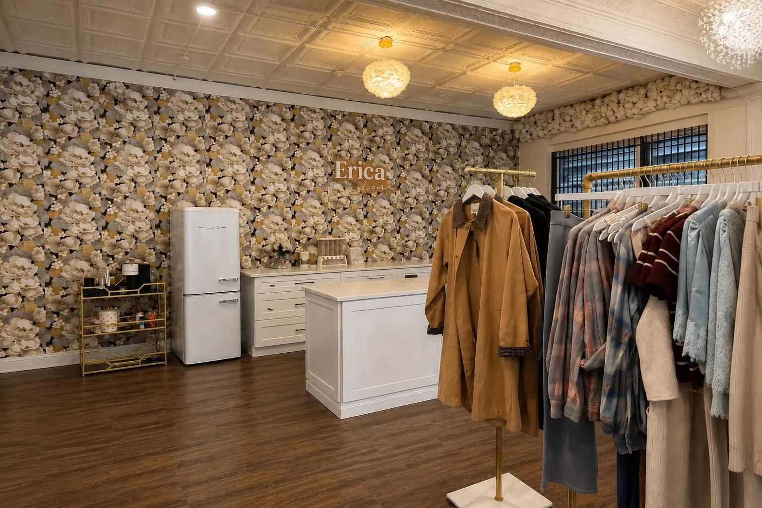 Inside Erica Logan Clothing Boutique: brass rails of women's clothing beside the checkout counter, against floral wallpaper under a pressed-tin ceiling.